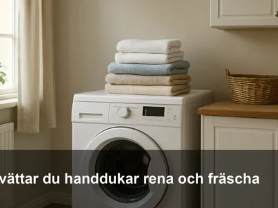 Ny-tvättade vita och färgade handdukar vikta i en hög på en tvättmaskin i ett ljust tvättrum.