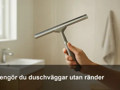 Hand som skrapar vatten från en glasduschvägg med fönsterskrapa – klart glas utan ränder.