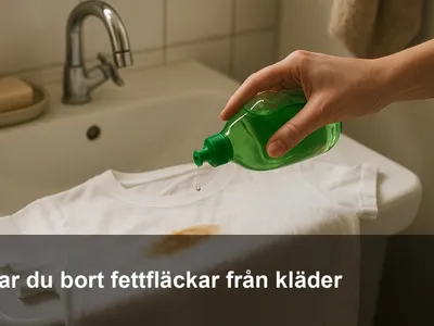 Diskmedel masseras in på en fettfläck på en mörk t-shirt vid handfatet.