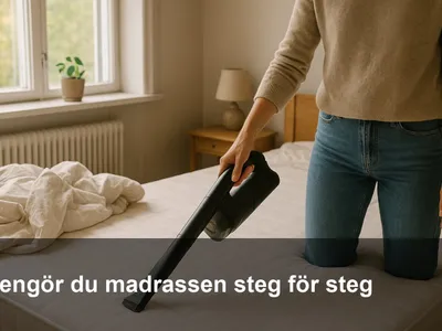 En person dammsuger en avklädd madrass noggrant med ett smalt munstycke längs sömmarna.
