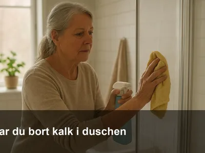 Hand som torkar bort kalkfläckar på en glasduschvägg med mikrofiberduk