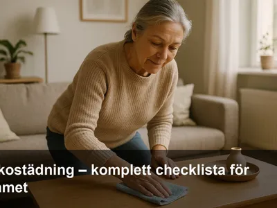 Kvinna i 60-årsåldern torkar av ett soffbord med mikrofiberduk under veckostädning i ett ljust vardagsrum.