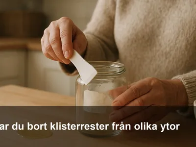 Hand som skrapar bort klisterrester från en glasburk med plastskrapa, lite olja och mikrofiberduk bredvid.