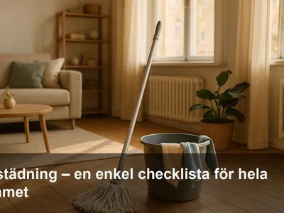 Ljust svenskt vardagsrum med öppna fönster, städhink, mopp och trasor i vårsol.