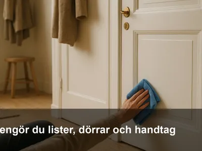 Person som torkar av vit dörr och golvlist med blå mikrofiberduk i en hall.